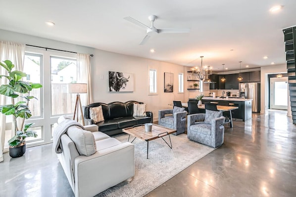 A modern living room with a sofa, armchairs, a coffee table, and a dining area.