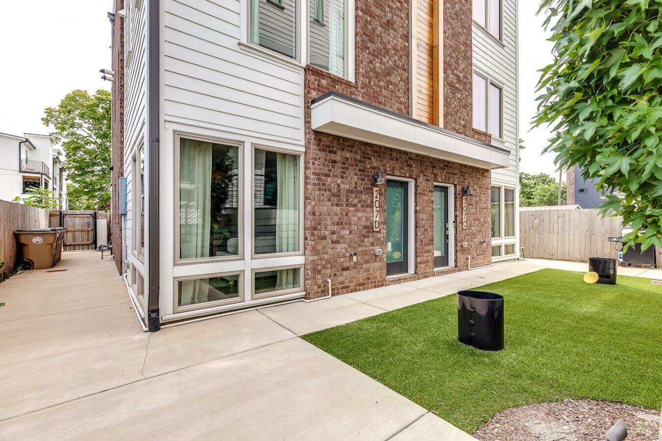 A modern two-story residential building with large windows and a well-maintained lawn.