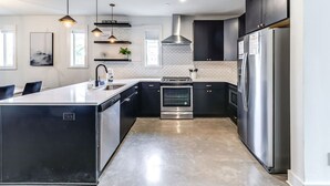 Una cocina moderna con una isla central, electrodomésticos de acero inoxidable e iluminación colgante.