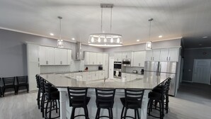 A modern kitchen with white cabinets, stainless steel appliances, and a central island with bar stools.