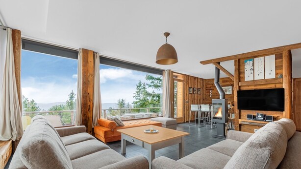 A modern living room with a large window, a fireplace, and a dining area. - Grand Chalet Standing Avec Jacuzzi à Chamrousse ski 1750 (Chamrousse)