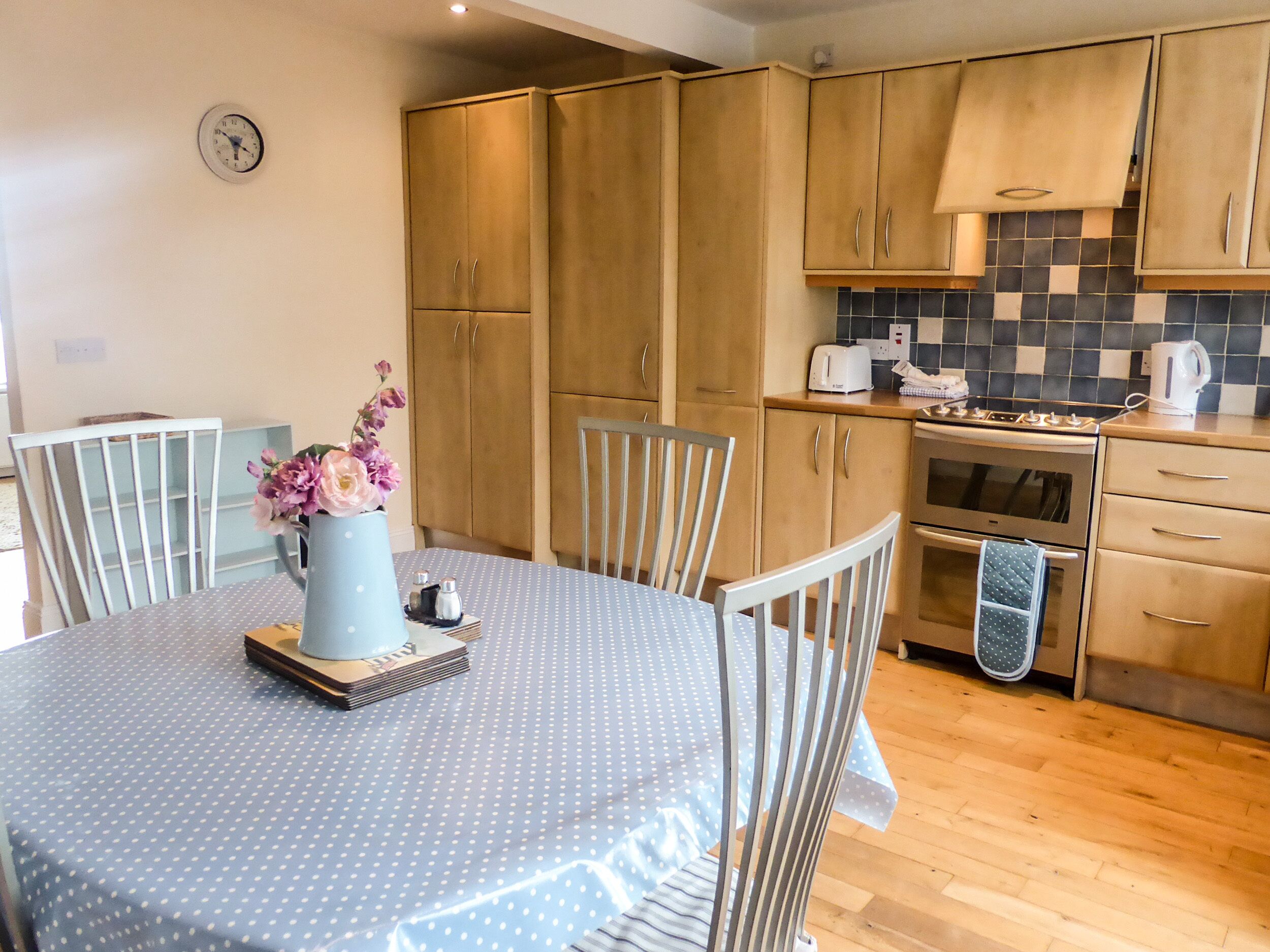 A kitchen with wooden cabinets, a stove, and a dining table with chairs.