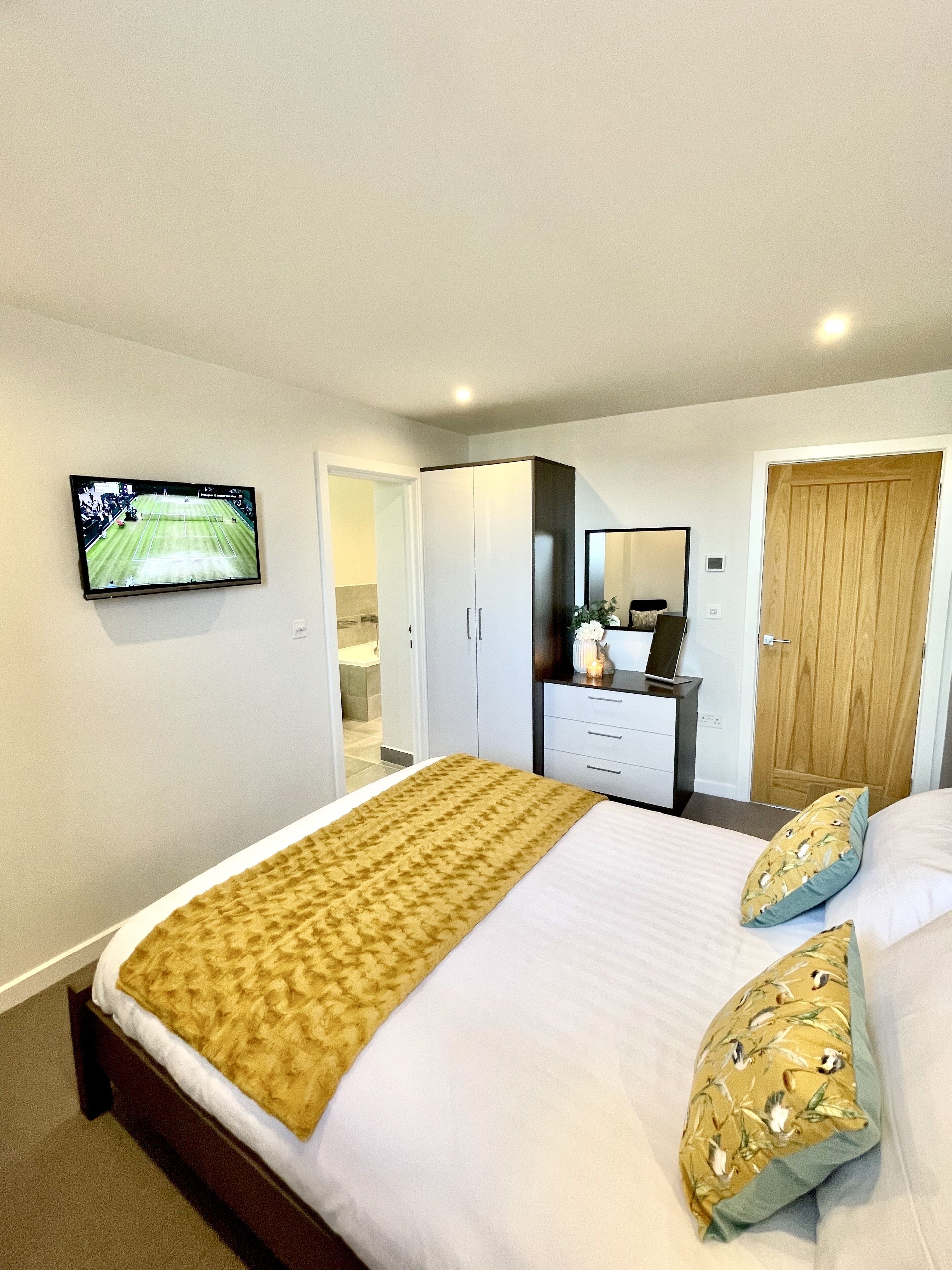A hotel room with a bed, a TV mounted on the wall, a wardrobe, and a door.