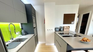 A modern kitchen with grey cabinets, a wooden floor, and a bright green backsplash. - Apartment Twelve (Shrewsbury)