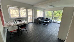 A modern living space with a dining area, a sofa, and a coffee table. - Apartments-Saaldorf WG1 with terrace and view of the reservoir (Bad Lobenstein)
