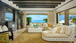 Een luxueuze woonkamer met een groot raam met uitzicht op de oceaan, een comfortabele bank, een bijzettafeltje en een decoratieve open haard.