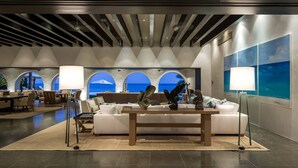 A modern lobby with a white sofa, a coffee table, and a view of the ocean through arched windows. - Luxurious 7 BR Beachfront Casa Oliver w/ WiFi, Pool, Home Theatre, Gym + More! (San Jose del Cabo)