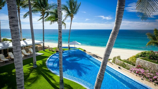 A swimming pool with a view of the ocean, surrounded by palm trees and lounge chairs. - Luxurious 7 BR Beachfront Casa Oliver w/ WiFi, Pool, Home Theatre, Gym + More! (San Jose del Cabo)