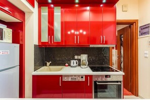 A kitchen with red cabinets, a white refrigerator, a coffee maker, a toaster, and a dishwasher.