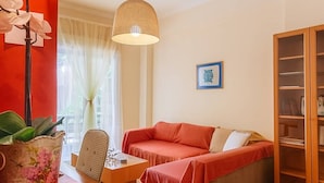 En hyggelig stue med en rød sofa, et træskab og en hængende lampe.