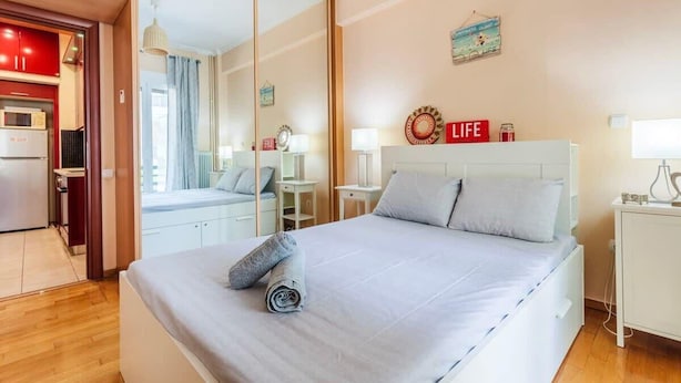 Et hotelværelse med seng, spejl, skrivebord og tekøkken.