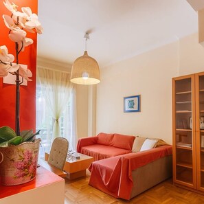 A cozy living room with a red sofa, a wooden cabinet, and a hanging lamp. - Athens Strawberry Hideaway - City Cozy Gem (Athina)