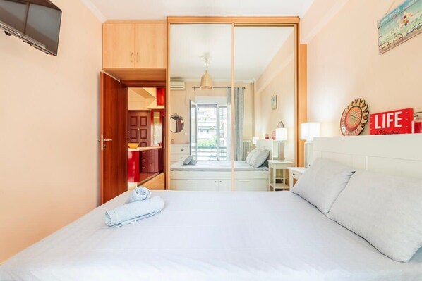 A bedroom with a bed, a wardrobe, a desk, and a television.