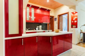A kitchen with red cabinets, a white countertop, and a black backsplash. - Athens Strawberry Hideaway - City Cozy Gem (Athina)