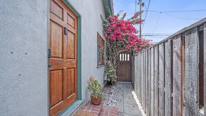 A narrow alleyway with a wooden door labeled 'B', a potted plant, and a wooden fence. - Venice Beach Cottage with incredible outdoor space!! (Venice)