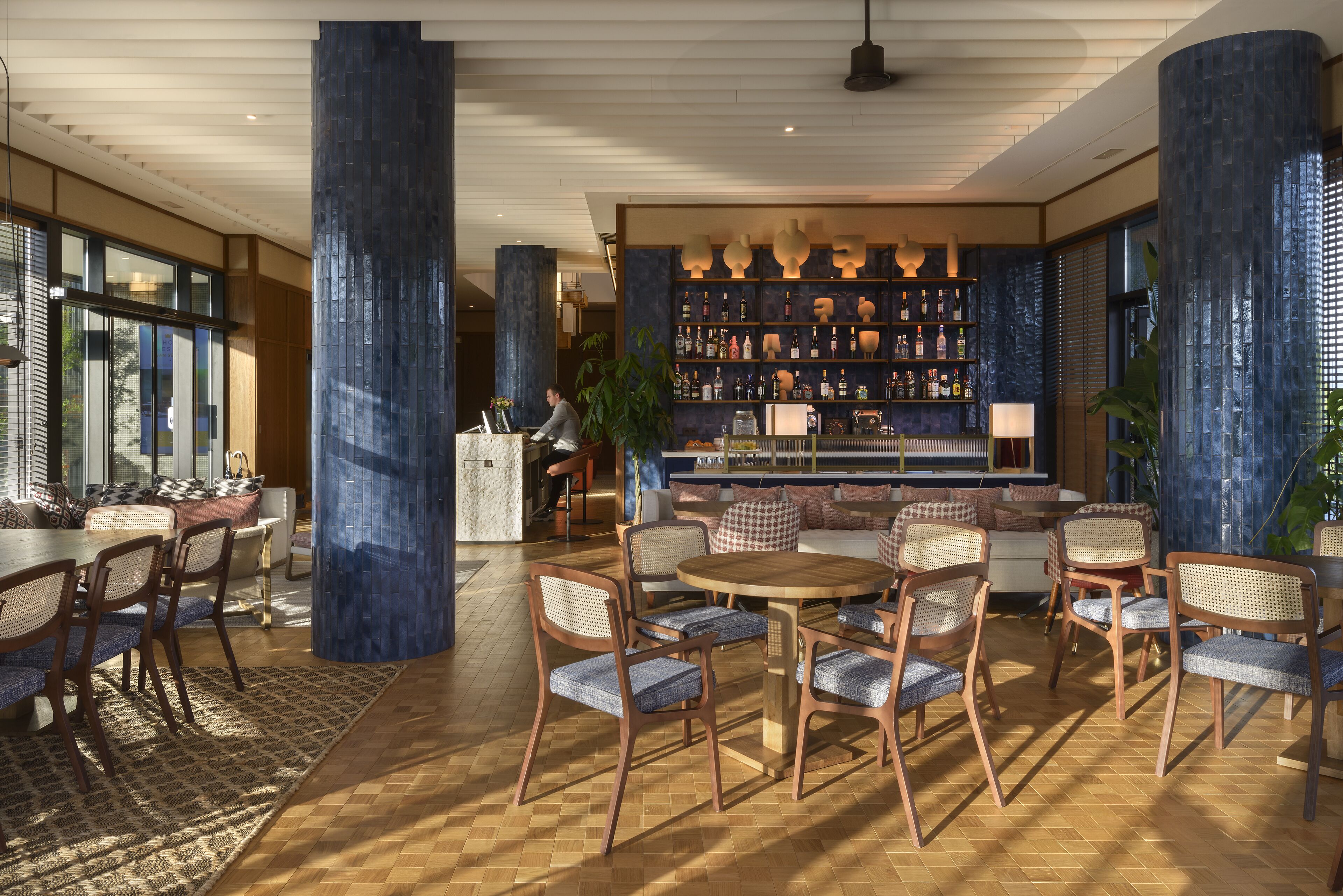 Eine geräumige Lobby mit Barbereich, Holzmöbeln und großen Fenstern.