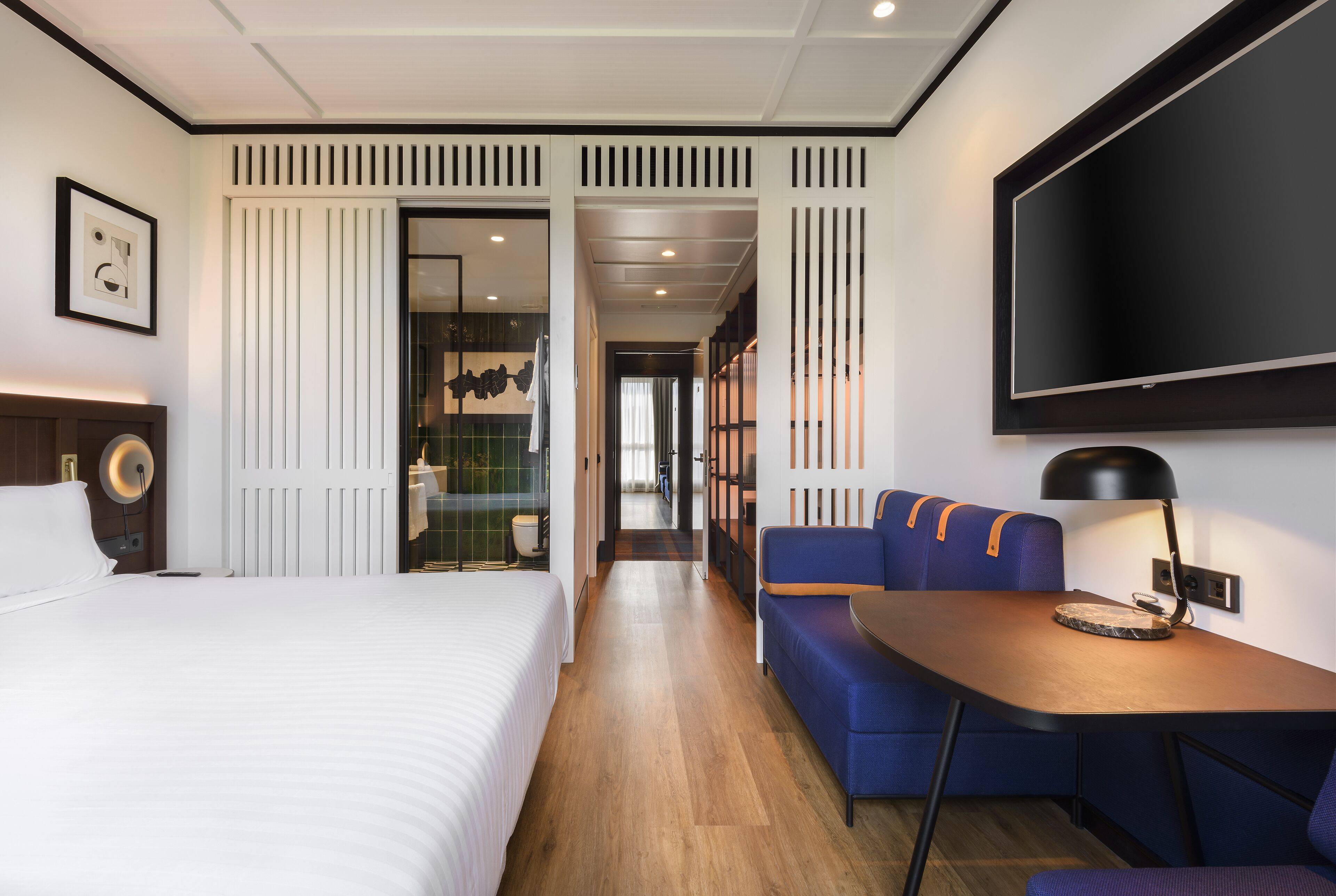 Une chambre d’hôtel comprenant un lit, un coin salon, une télévision et une salle de bain visible à travers une porte.