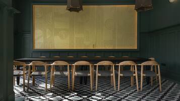 Un comedor con una mesa larga y sillas, pisos de baldosas con diseño y un panel decorativo en la pared.