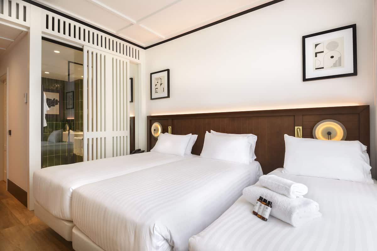 Une chambre d’hôtel avec deux lits, une tête de lit en bois et un grand miroir.