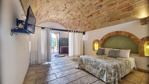 A bedroom with a stone ceiling, a bed with floral bedding, and a stone fireplace. - 3-apt house with private pool, 250m from beach (Torre Vado)