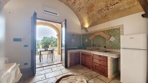 A kitchen with an open archway leading to a patio area, a sink, cabinets, and a refrigerator. - 3-apt house with private pool, 250m from beach (Torre Vado)