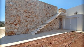 Un edificio moderno con una pared de mosaicos de piedra, una escalera blanca y un garaje.
