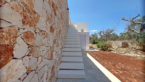 A modern building with a stone exterior and a white interior, featuring a staircase leading to a door.