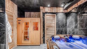 A sauna room with a wooden door, a steam shower, and a marble-tiled wall.