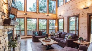 A spacious cabin with a stone fireplace, large windows, and a cozy seating area.