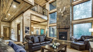 A spacious living room with a fireplace, leather sofas, and a stone accent wall. - "Rustic Mountain Lodge" Bunk Room, Outdoor Entertaining, Pets (Broken Bow)