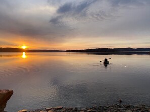 A kayaker on a calm lake at sunset. - Sunset Cabin - Secluded retreat on Beaver Lake (Rogers)