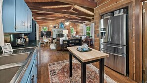 A spacious kitchen with wooden beams, a large refrigerator, and a dining area with a table and chairs.