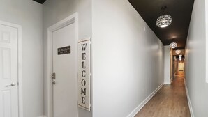 Un couloir avec une pancarte indiquant « BIENVENUE », une porte sur laquelle on peut lire « LOS ANGELES, CA », et un logo « GENEVA LAKES VACATIONS ».