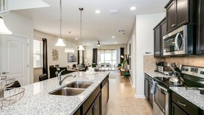Una cocina moderna con encimeras de granito, electrodomésticos de acero inoxidable y una isla central con lavamanos.