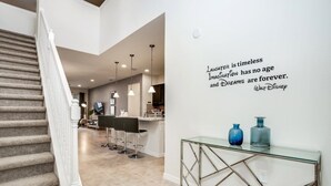 Un interior moderno con una escalera, una zona de cocina y una pared con una cita motivacional.