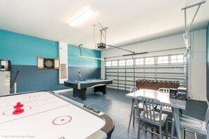 A recreational room with a foosball table, pool table, and dartboard.