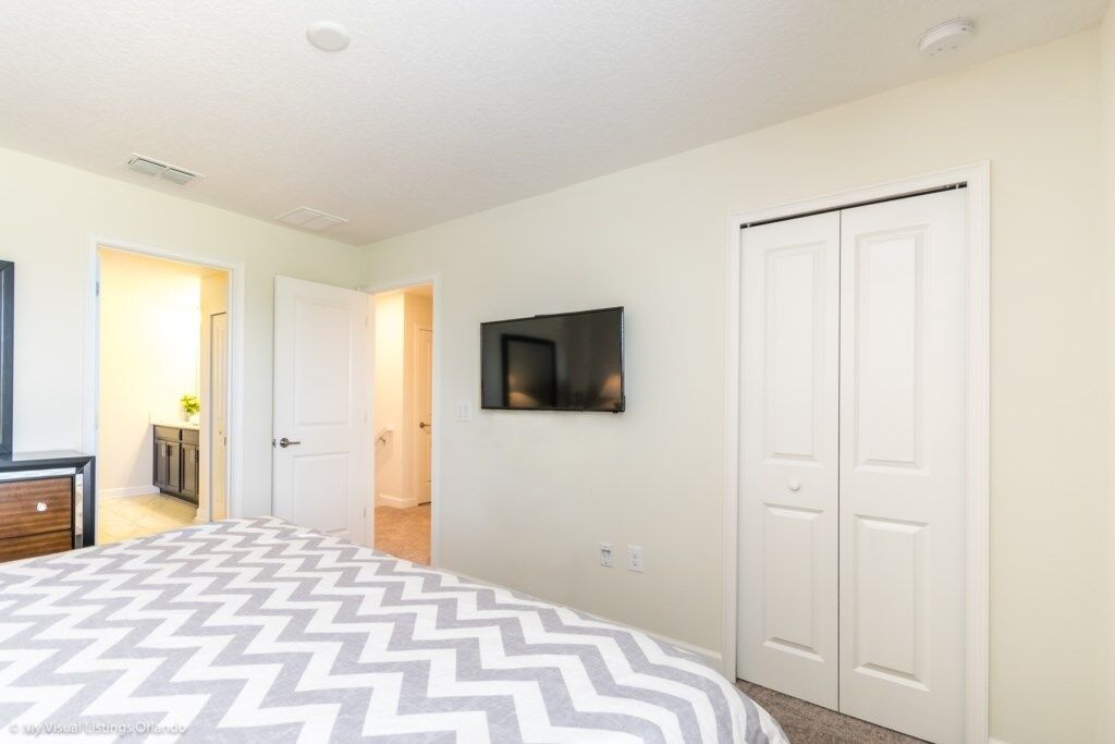 A bedroom with a bed, a TV mounted on the wall, and a closet.