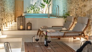 A sunlit room with a pool, lounge chairs, and a table with wine glasses. - Dianthus Residence, Heated Pool & in-pool Whirlpool (Adele)