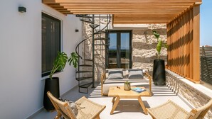 A modern outdoor seating area with a wooden pergola, stone walls, and a spiral staircase. - Dianthus Residence, Heated Pool & in-pool Whirlpool (Adele)