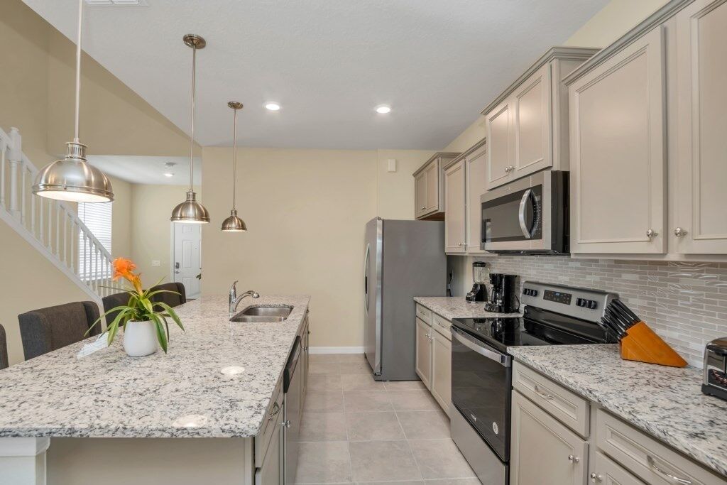 A kitchen with granite countertops, stainless steel appliances, and pendant lighting.