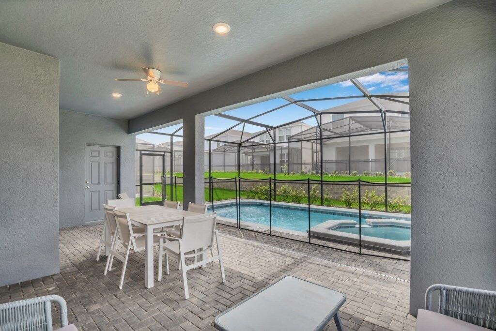 Un patio abrité avec une piscine, des sièges d’extérieur et une vue sur un quartier résidentiel.
