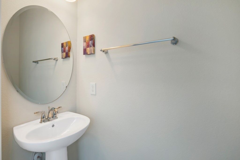 A bathroom with a white sink, a round mirror, and a towel rack.