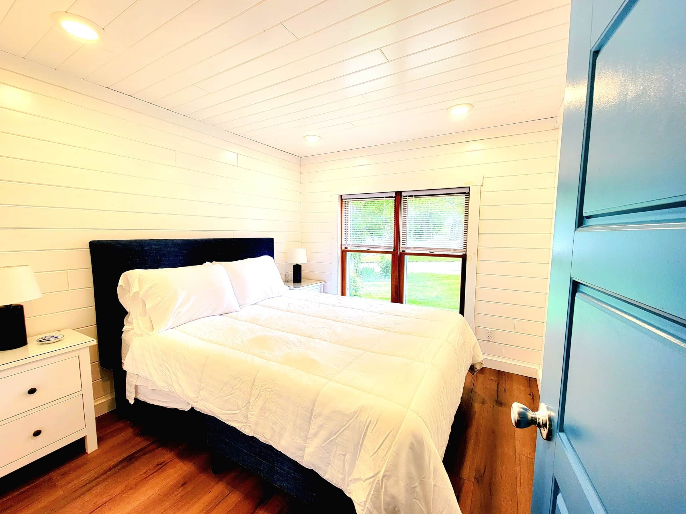A bedroom with a bed, nightstand, and window.