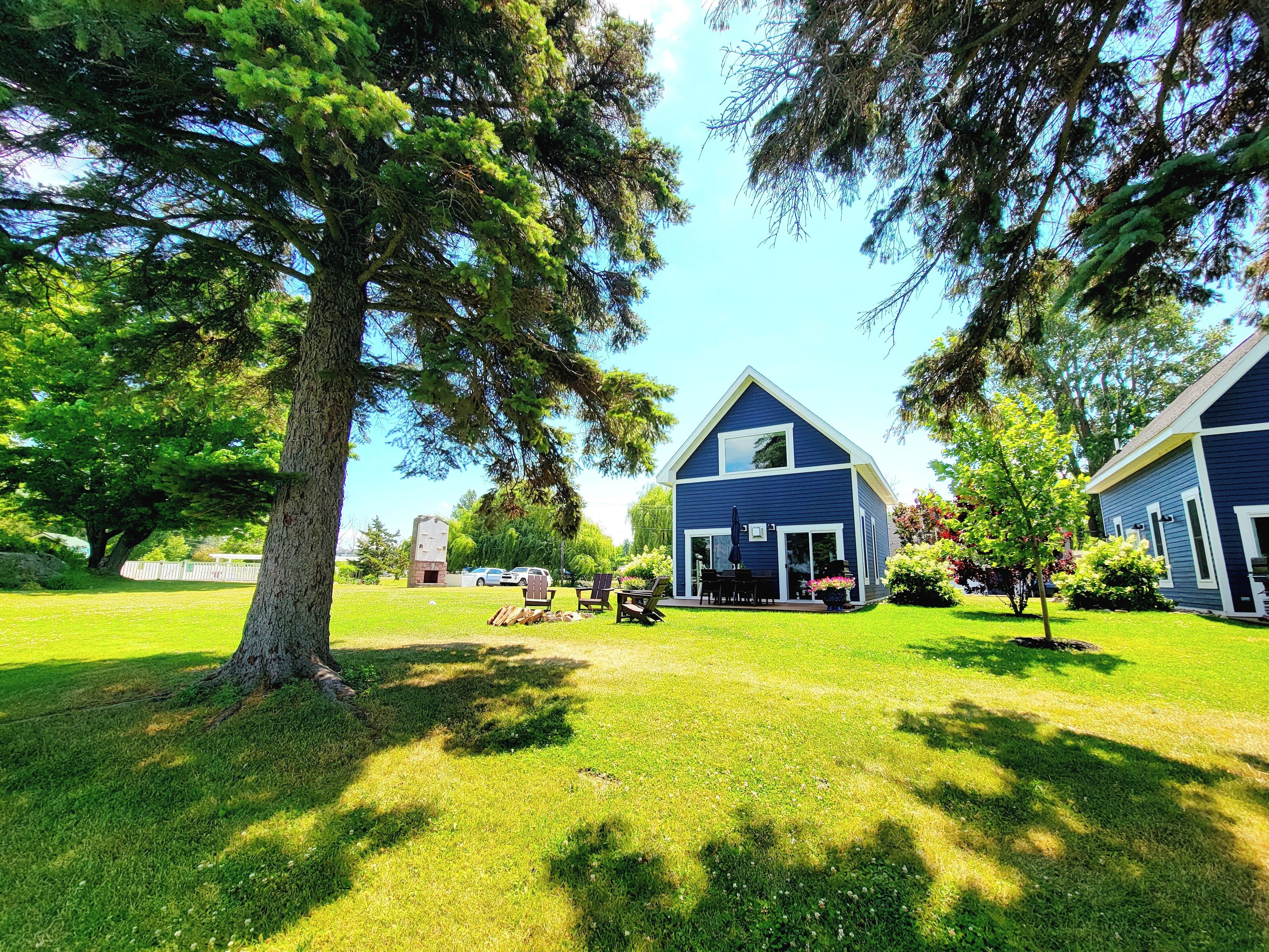 A two-story house with a large lawn, a patio with outdoor furniture, and a garage.