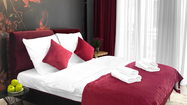 A modern hotel room with a large bed, red and white bedding, a decorative wall mural, a round light fixture, and sheer curtains. - Starowiślna 41-43 by PI Apartments (Kraków)