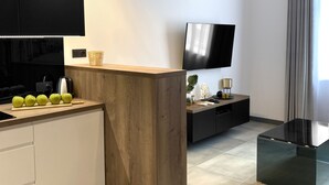 A modern kitchen with a wooden island, a built-in oven, and a flat-screen TV. - Starowiślna 41-43 by PI Apartments (Kraków)