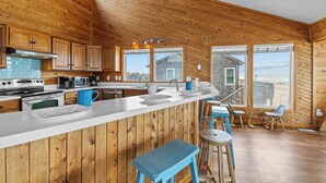 A kitchen with wooden walls, a large window, and a view of the beach. - Oceanfront Dog Friendly Home w/ Hot Tub & Grill (Avon)