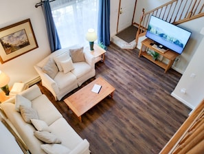 Een woonkamer met een bank, salontafel en een televisie op een houten dressoir.