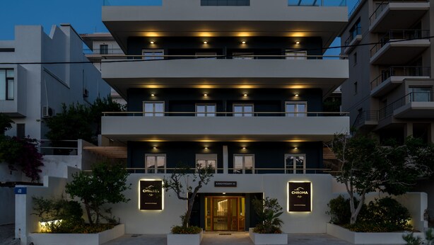 A modern multi-story hotel with a prominent entrance, balconies, and illuminated signage. - CHROMA Lodge Rafina (Rafina-Pikermi)