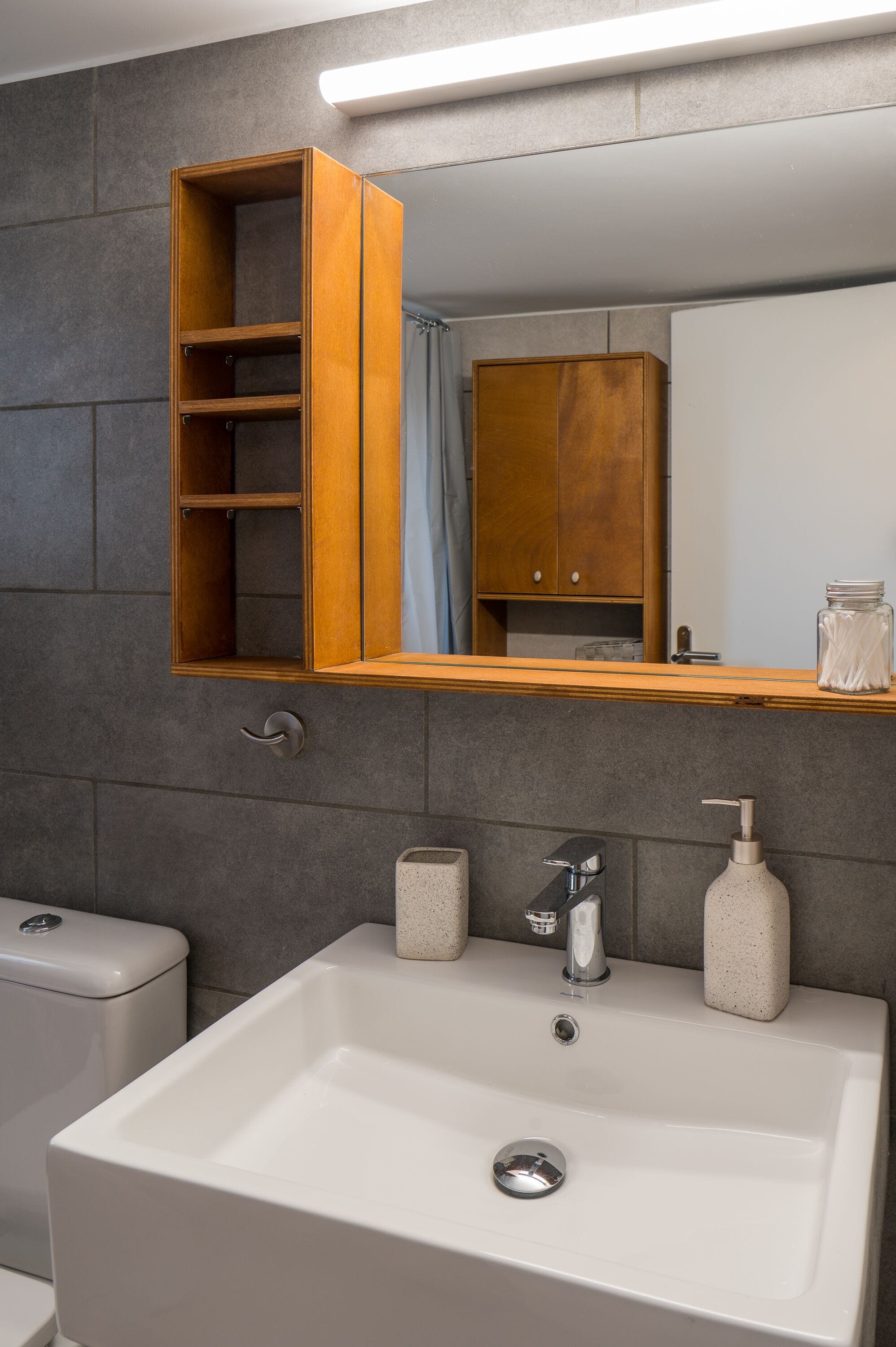 A bathroom with a white sink, a wooden medicine cabinet, and a mirror above the sink.
